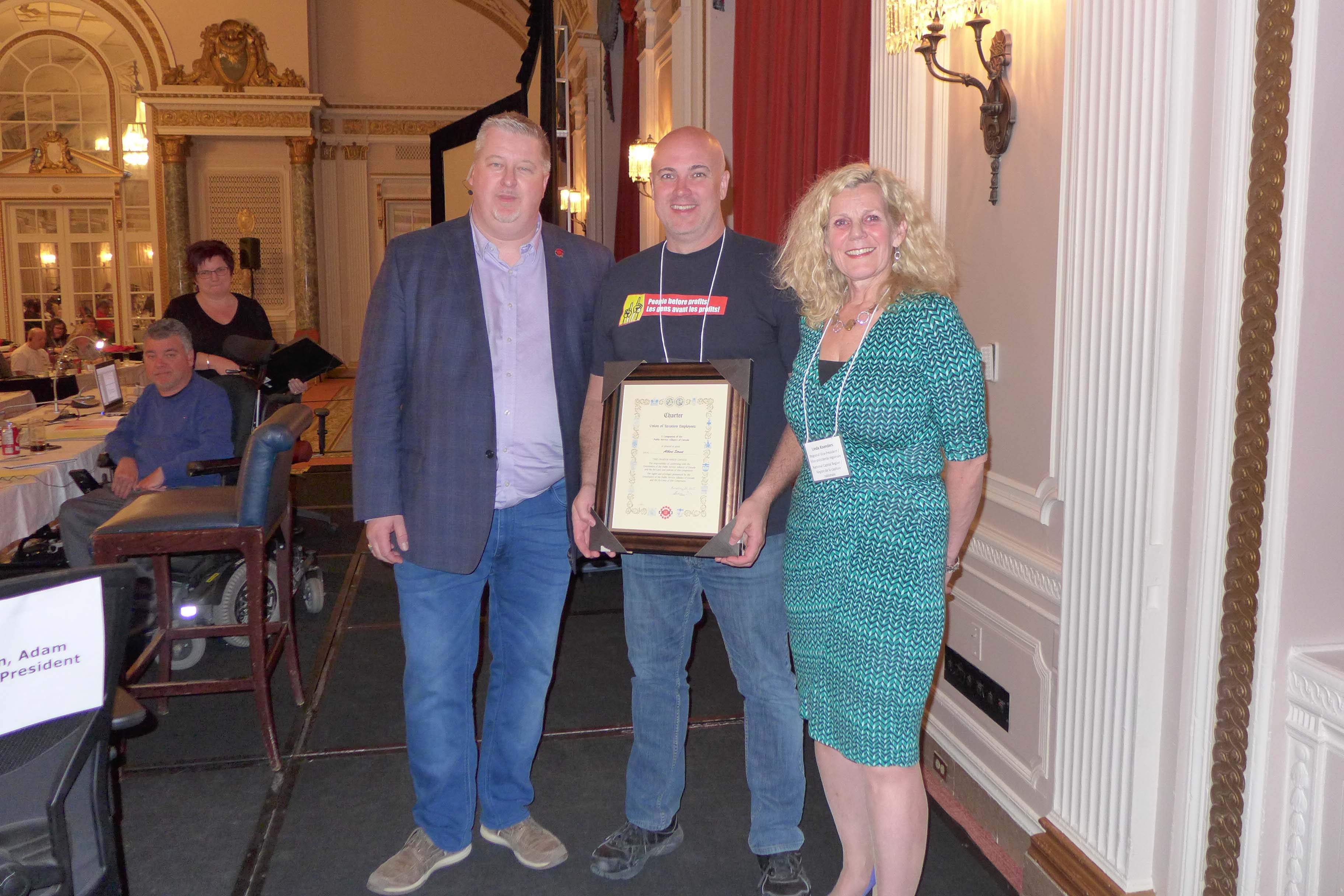 Le président national, Marc Brière et Linda Koenders, VPR pour la RCN, présentent Scott Henneberry, président de la section locale 70022 - rue Albert, avec la charte de la section locale