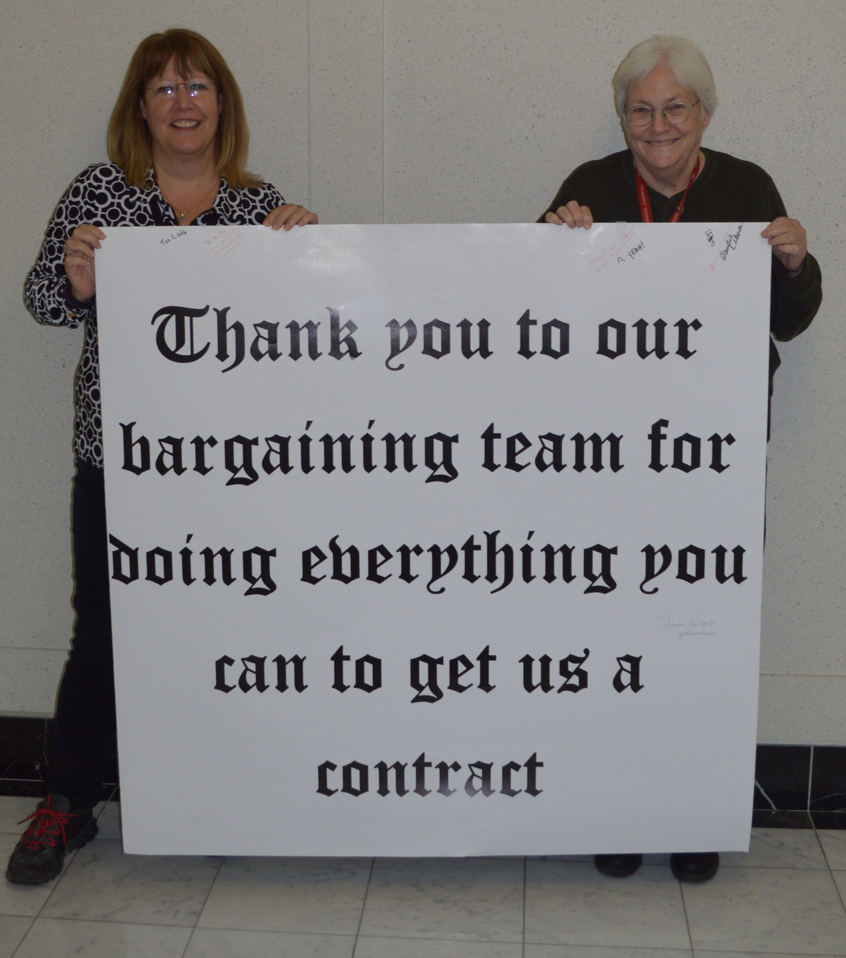 Robin Johnson and Linda Collins posing with a large card that the members signed