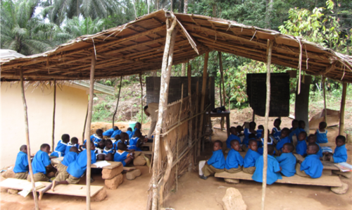 enfants en uniforme scolaire assis sur des bancs dans une école en plein air